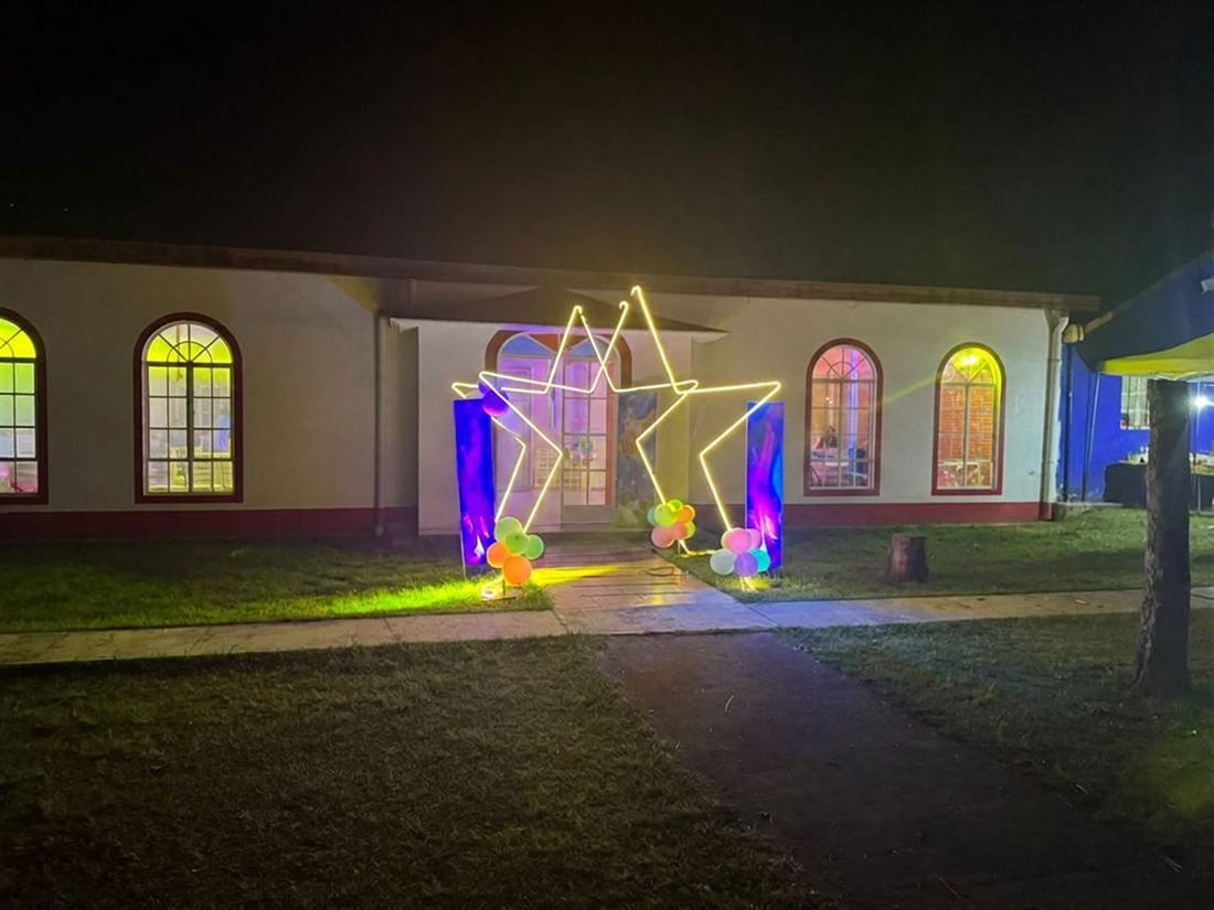 El salón de noche visto desde el jardín, con las ventanas de arco iluminadas por dentro y una estrella de luces en la entrada.